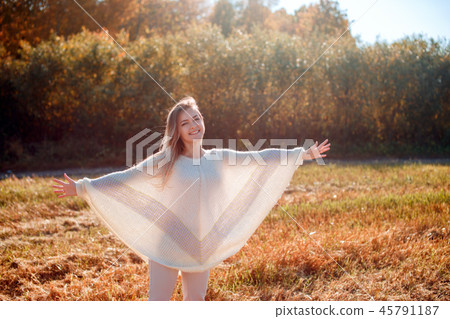 Cheerful girl with raised hands on the field in warm autumn season. Cheerful girl with raised hands on the field in warm autumn season. 45791187