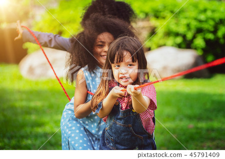Happy children playing tug of war in the park. Happy children playing tug of war in the park. 45791409