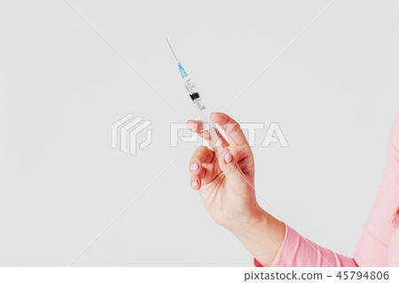 Disposable syringe in hand on gray background Disposable syringe in hand on gray background 45794806