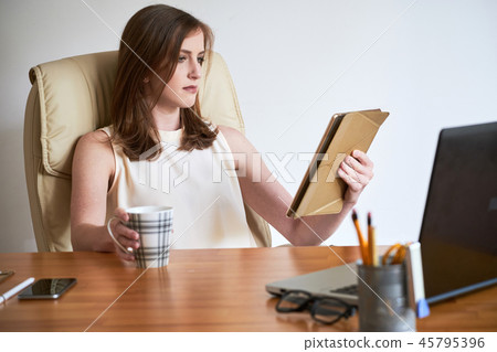 Contemporary businesswoman with tablet and coffee Contemporary businesswoman with tablet and coffee 45795396