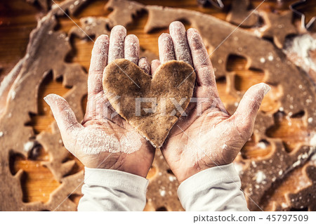 Christmas baking and gingerbread heart in hands. 45797509