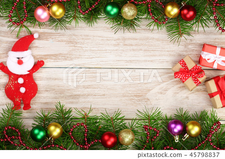 Christmas frame made of fir branches decorated with balls, Santa Claus and boxes on a light wooden Christmas frame made of fir branches decorated with balls, Santa Claus and boxes on a light wooden 45798837