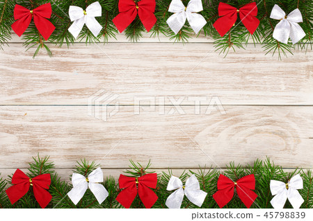 Christmas frame made of fir branches decorated with bows on a light wooden background Christmas frame made of fir branches decorated with bows on a light wooden background 45798839