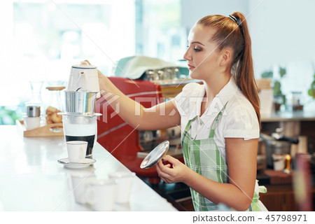 Young woman preparing fresh coffee at counter 45798971