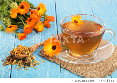 Calendula tea with fresh and dried flowers on blue wooden background Calendula tea with fresh and dried flowers on blue wooden background 45801135