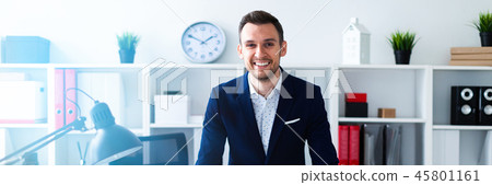 A young man stands in the office near the table and puts his hands on him. A young man stands in the office near the table and puts his hands on him. 45801161