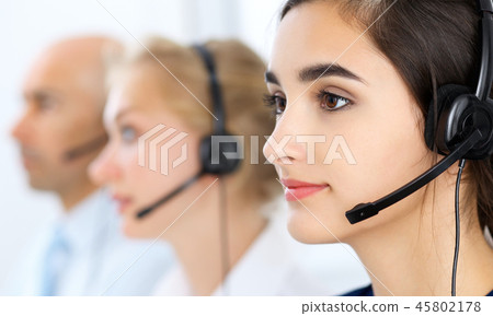 Call center operators at work. Focus at beautiful latin american woman in headset 45802178