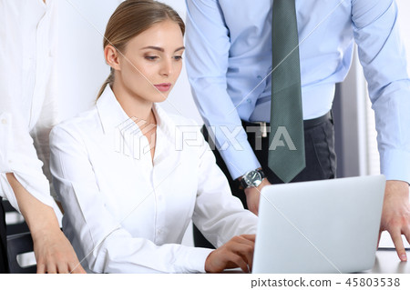 Group of business people using laptop computer while standing in office. Meeting and teamwork Group of business people using laptop computer while standing in office. Meeting and teamwork 45803538