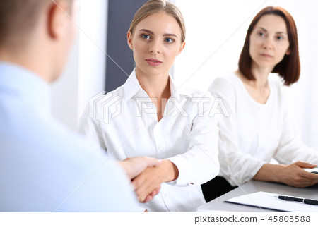 Business handshake by blonde woman and her partner at meeting. Concept of success and agreement Business handshake by blonde woman and her partner at meeting. Concept of success and agreement 45803588