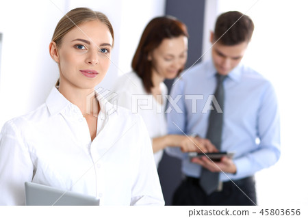 Beautiful blonde businesswoman standing straight in a brightly lit office at the background of Beautiful blonde businesswoman standing straight in a brightly lit office at the background of 45803656