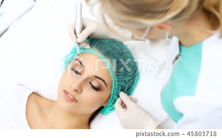 Professional beautician doing eyebrow tattoo at woman face. Permanent brow makeup in beauty salon 45803718