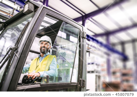 Mature industrial man engineer sitting in a forklift in a factory. 45807079