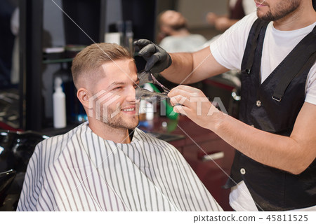 Barber removing black mask from face of man in barber shop 45811525