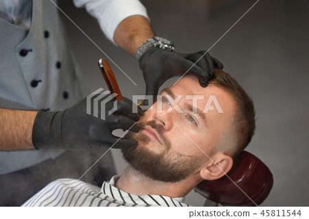 View from above of man on chair while barber shaving beard 45811544