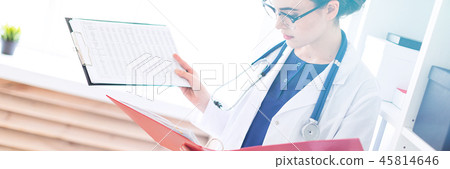A beautiful young girl in a white robe stands near the shelter and holds in her hands sheets with 45814646