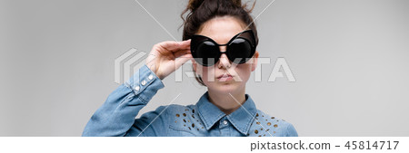 Young brunette girl in black glasses. Cat glasses. The hair is gathered in a bun. The girl adjusts Young brunette girl in black glasses. Cat glasses. The hair is gathered in a bun. The girl adjusts 45814717