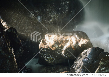 waterfall in cave behind rock in forest 45814767