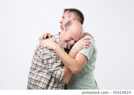 Elder father is crying on his son shoulder and feeling upset cause from his mistake. 45814824