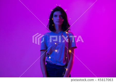 Portrait of young woman with hanging christmas lights on her body 45817063