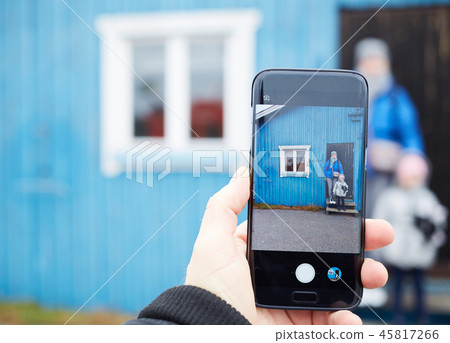 Mans hand making photo of a little girl and woman with a mobile phone. Selective focus on a mobile Mans hand making photo of a little girl and woman with a mobile phone. Selective focus on a mobile 45817266