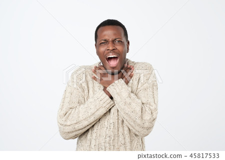 Upset funny african american man in sweater, holding hands on neck while choking Upset funny african american man in sweater, holding hands on neck while choking 45817533