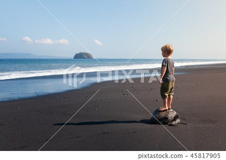 Child stand on big stone on black sand sea beach Child stand on big stone on black sand sea beach 45817905