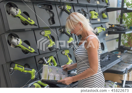 Blond woman is viewing catalog at hardware store Blond woman is viewing catalog at hardware store 45822673