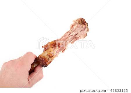 Close up and isolated image of hand holding a nibbled turkey leg on white background. 45833125