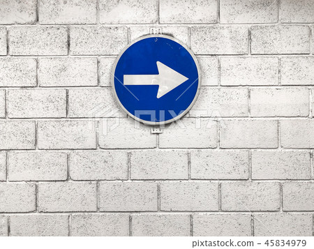 white arrow on blue road sign hanging on wall white arrow on blue road sign hanging on wall 45834979