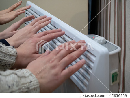 family warming up near home electric heater 45836339