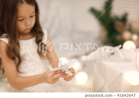 child girl makes paper snowflakes for decoration Christmas tree 45842647