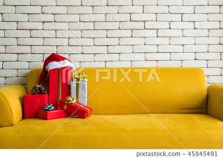 Gift boxed on yellow sofa with white brick wall. 45845491