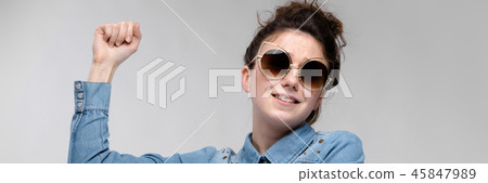 Young brunette girl in black glasses. Cat glasses. The hair is gathered in a bun. The girl points a 45847989