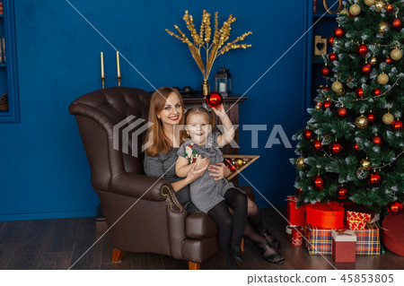 Mom and daughter are sitting on a leather chair in 45853805