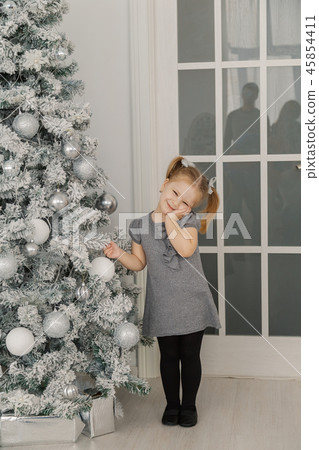 A little girl is standing by a Christmas tree and A little girl is standing by a Christmas tree and 45854411