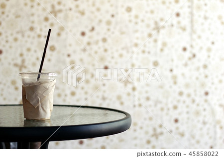 A glass of iced coffee on a glass table with a bro 45858022