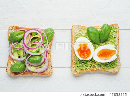 Two avocado toasts on white wooden background Two avocado toasts on white wooden background 45858235