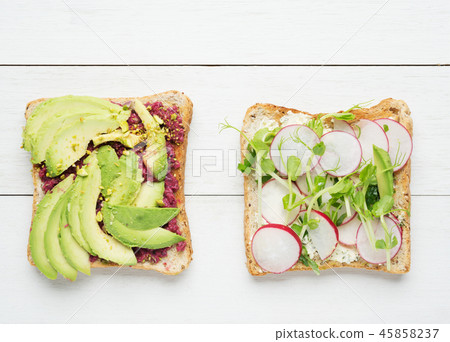 Two avocado toasts on white wooden background Two avocado toasts on white wooden background 45858237