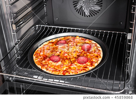Cooking homemade pizza with salami sausage in oven 45859868