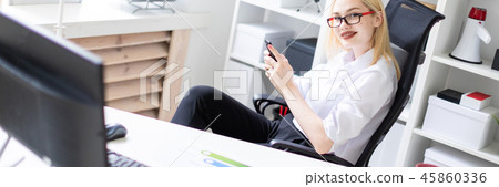 A young girl sitting in the office and holding a phone. A young girl sitting in the office and holding a phone. 45860336