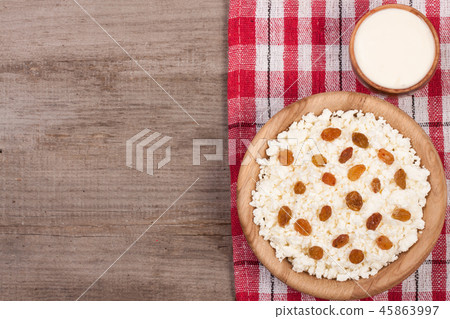 Cottage cheese in bowl with sour cream and raisins on old wooden background with copy space for your 45863997