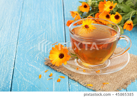 Calendula tea with fresh flowers on blue wooden background Calendula tea with fresh flowers on blue wooden background 45865385
