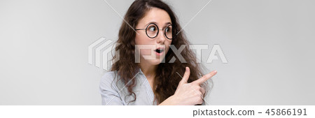 Portrait of a young girl in glasses. Beautiful young girl on a gray background. A young girl in a 45866191