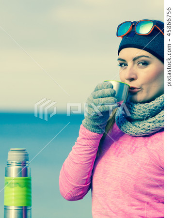 Fit woman in cold day warming up drink tea Fit woman in cold day warming up drink tea 45866756