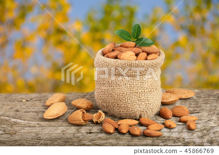 Almonds with leaf in bag from sacking on a wooden table with blurred garden background 45866769