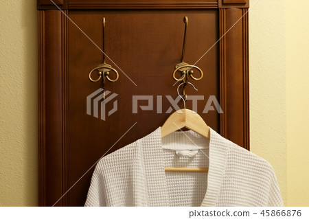 White textile robe is hanging on the hook 45866876