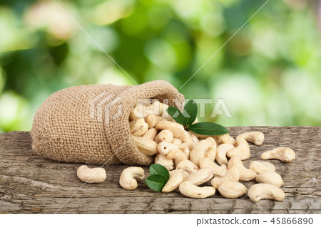 cashew nuts with leaf in bag on a wooden table with blurred garden background cashew nuts with leaf in bag on a wooden table with blurred garden background 45866890