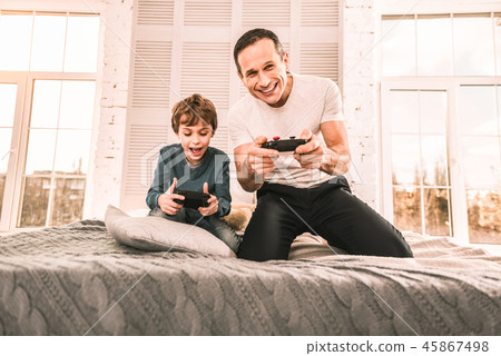 Father being proud of himself for beating his son in a game. Father being proud of himself for beating his son in a game. 45867498