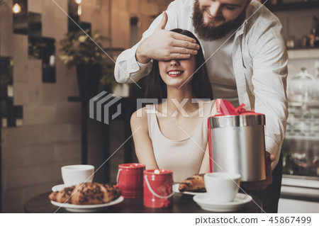 A man gives a gift to a girl with closed eyes A man gives a gift to a girl with closed eyes 45867499