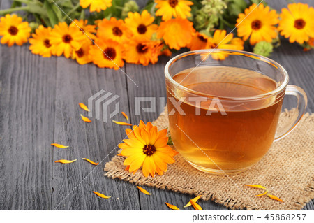 Calendula tea with fresh flowers on black wooden background Calendula tea with fresh flowers on black wooden background 45868257